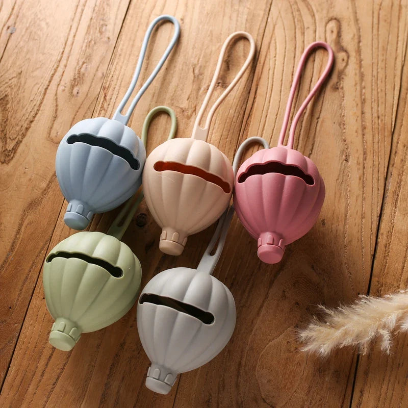 Die Hello World Schnullertasche Heissluftballon Blau (7x22,5cm) ist ein niedlicher Silikon-Schnullerhalter mit Riemen, perfekt für Schnuller-Aufbewahrung und ein entzückendes Baby-Geschenk.