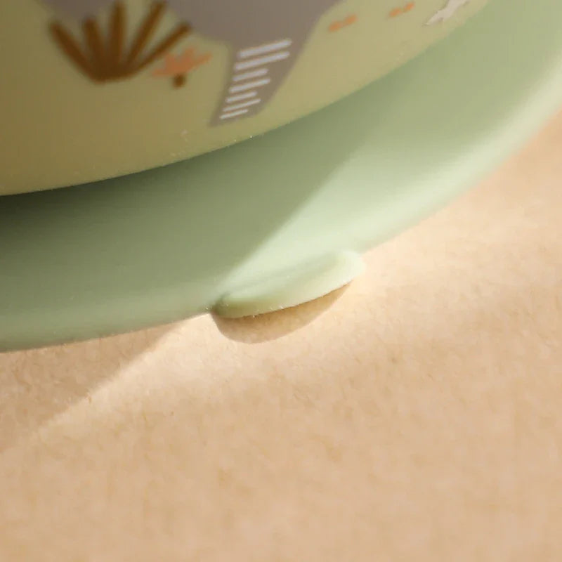 Nahaufnahme des Saugnapf-Sockels der Hello World Schüssel rund mit Motiv Grün [12x8cm], der auf einer glatten, beigen Oberfläche befestigt ist - wahrscheinlich dem Boden einer Schüssel mit Elefantenmotiv.