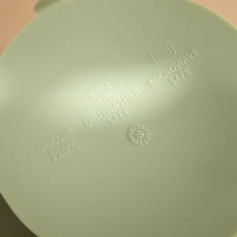 Nahaufnahme einer Hello World Schüssel rund mit Motiv Grün [12x8cm] mit geprägten Symbolen und Text, die zeigt, dass sie spülmaschinenfest, mikrowellenfest und hitzebeständig bis 220°C ist.