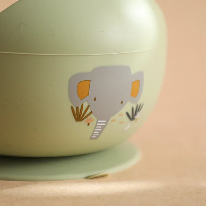 Eine Nahaufnahme der Hello World Schüssel rund mit Motiv Grün [12x8cm], mit einem Cartoon-Elefanten und einem Blattdruck auf einem beigen Hintergrund und Untergrund.