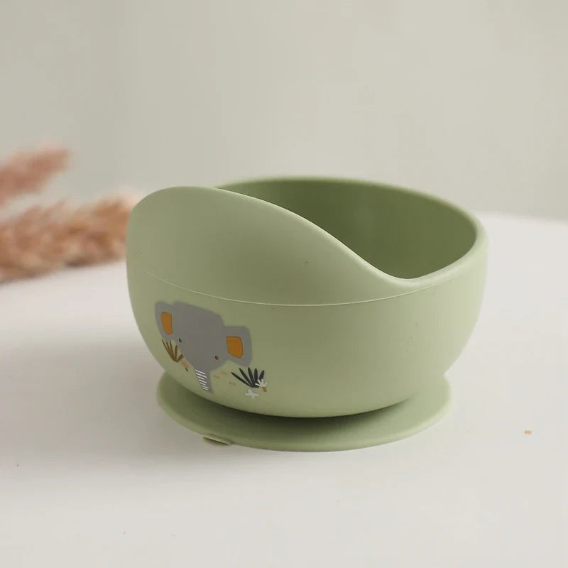 Die Hello World Schüssel rund mit Motiv Grün [12x8cm] aus Silikon mit rutschfestem Saugfuß und Elefanten Motiv ist auf einer weißen Oberfläche zu sehen.