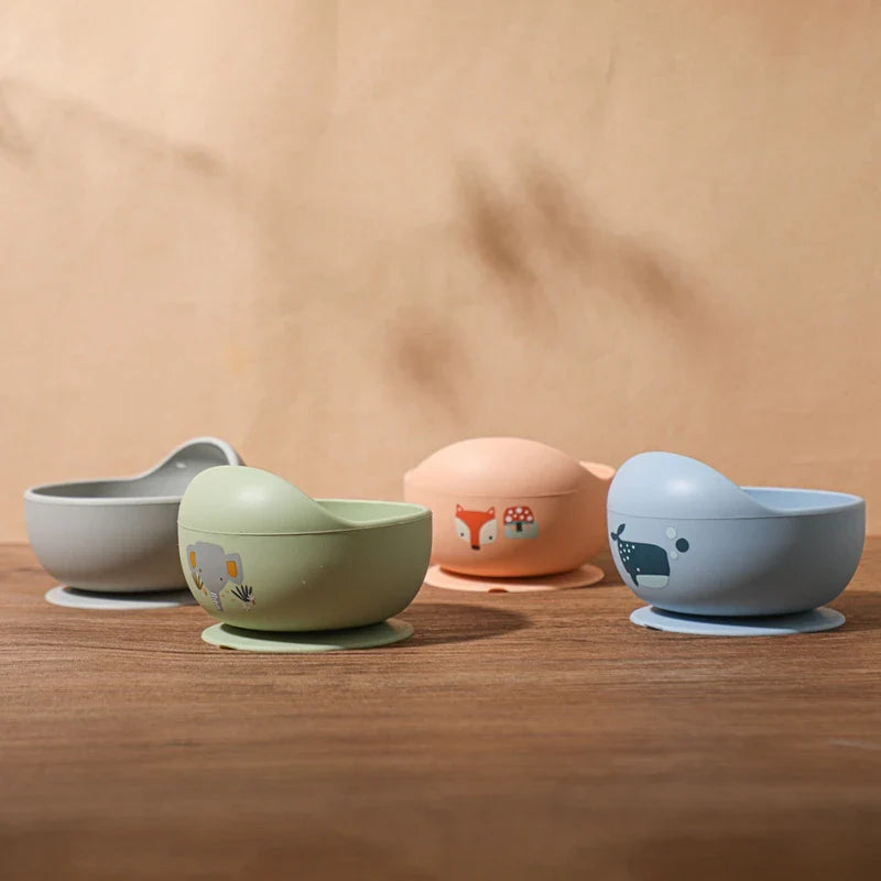 Vier orangefarbene Hello World Schüsseln rund mit Motiv [12x8cm] sitzen auf einer Holzfläche vor einem beigen Hintergrund. Jedes Kindergeschirr hat ein lustiges Design, einen Saugfuß und einen abgerundeten Rand.