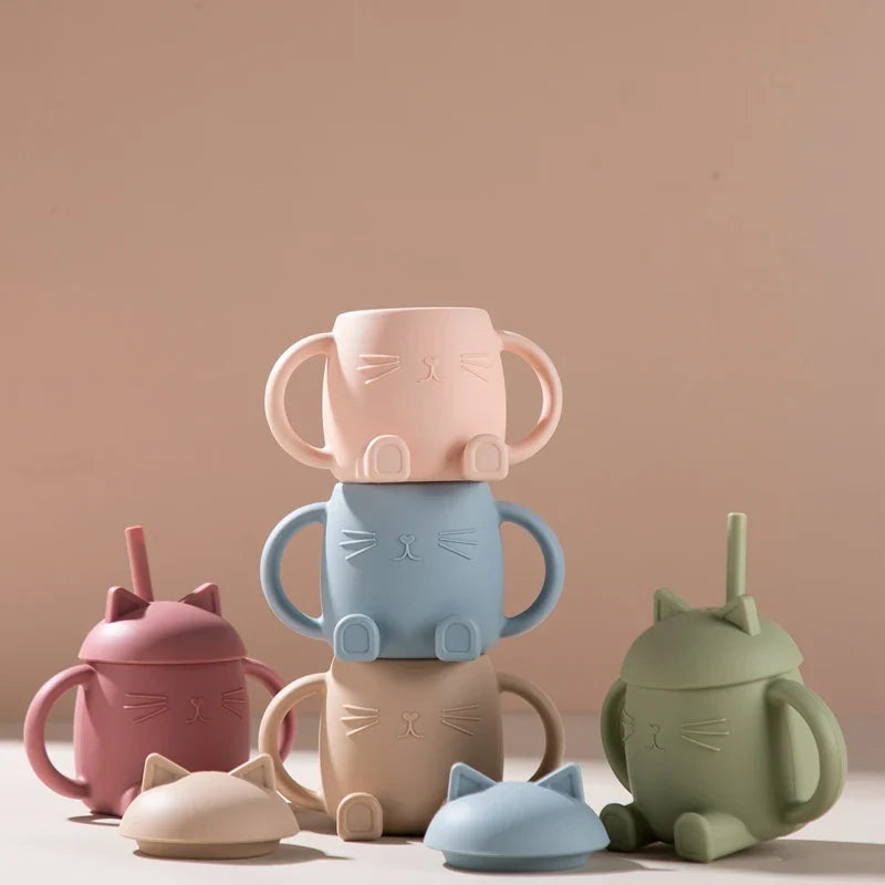 Ein Stapel Hello World Trinkbecher Katze sitzend Pink [13x11cm] in Katzenform mit Henkeln, niedlichen Gesichtern und in zartem Pastellrosa - perfekt für kleine Prinzessinnen! Einige enthalten Deckel und Strohhalme, mit zusätzlichen katzenförmigen Deckeln auf der Vorderseite.