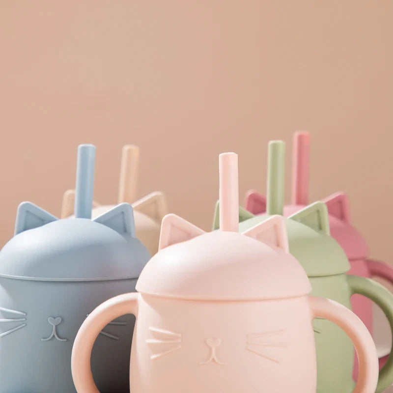 Mehrere Hello World Trinkbecher Katze sitzend Rosa [13x11cm] in Pastellfarben - blau, rosa, grün und beige - sind mit Henkeln, Deckeln mit Katzenmotiven und Strohhalmen ausgestattet. Diese Silikonbecher sind für Kinder zusammengestellt.