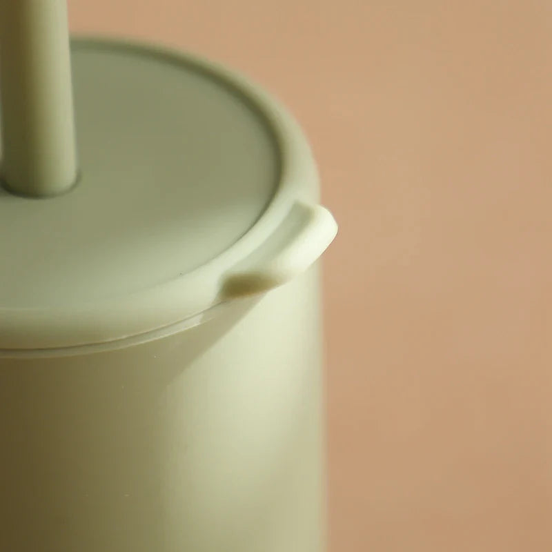 Eine Nahaufnahme des Hello World Trinkbechers mit Motiv Grün [6x12,5cm] mit passendem Deckel und Griff vor einem zartbeigen Hintergrund. Die glatte Textur des BPA-freien Bechers und die subtilen Schatten kommen wunderbar zur Geltung.