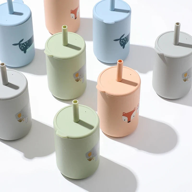 Mehrere Hello World Trinkbecher mit Motiv Grün [6x12,5cm], BPA-frei, mit Deckeln und Strohhalmen, sind auf einer weißen Fläche angeordnet und mit niedlichen Tiermotiven wie Rehen, Füchsen und Elefanten verziert.