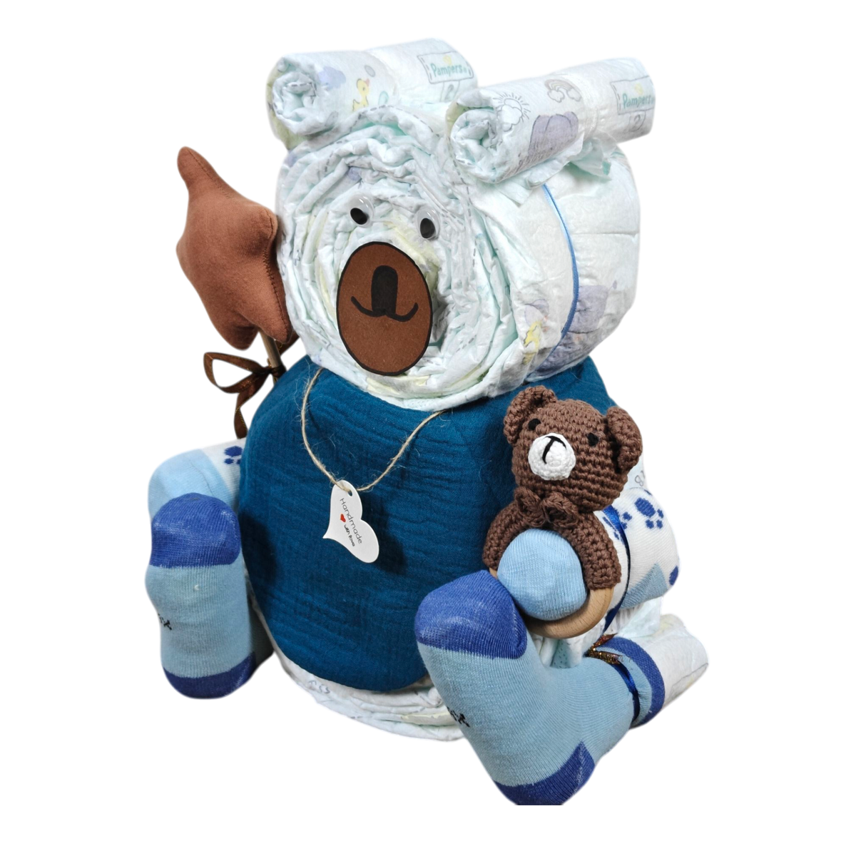 Das Windelgeschenk Teddy [33x35cm] von Hello World ist ein bärenförmiges Windelgeschenk mit blauem Stoff, Socken und einem gehäkelten Teddybär - komplett mit Filznase und Ohren - und eignet sich perfekt als charmantes Geschenk zur Geburt.
