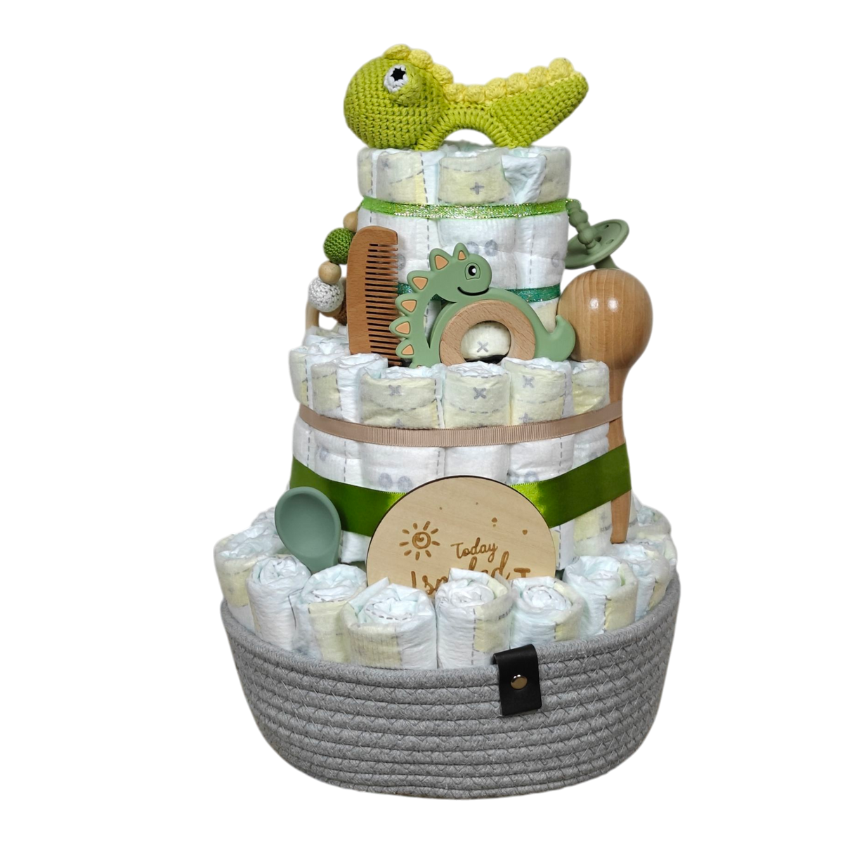 Die Hello World Windeltorte Dino [25x38cm] besteht aus drei Etagen, grünen und beigen Bändern und Babyutensilien: gehäkelter Dinosaurier, Holzkamm, Bürste, Beißring, Schnullerclip, Silikonlöffel und Meilensteinmarker - das perfekte Geschenk zur Geburt!.