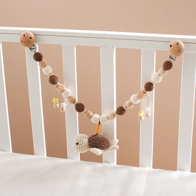 Ein weißes Krippengitter mit der Kinderwagenkette Schildkröte [30x31cm] von Hello World, gehäkelten Perlen aus Holz und gehäkelten Perlen und kleinen gelben Sternen. Ideal für entspannte Reisen.