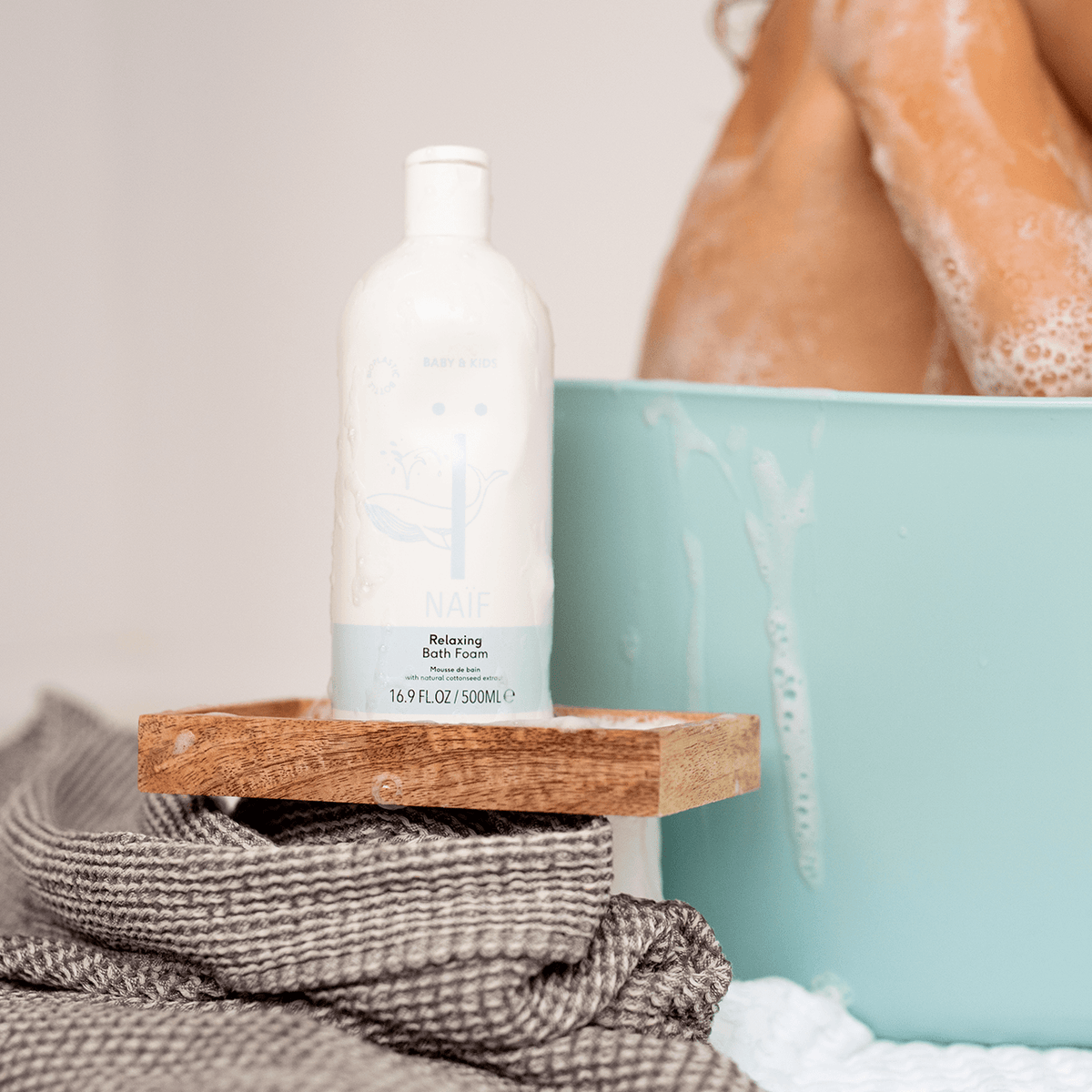 Bagnoschiuma Naïf Baby & Kids 500 ml accanto alla vasca da bagno per la cura delicata del bambino