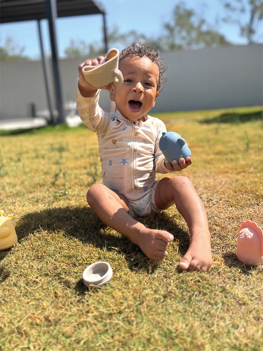 Child holds the Small Foot silicone bath toy set in his hand while playing outside.