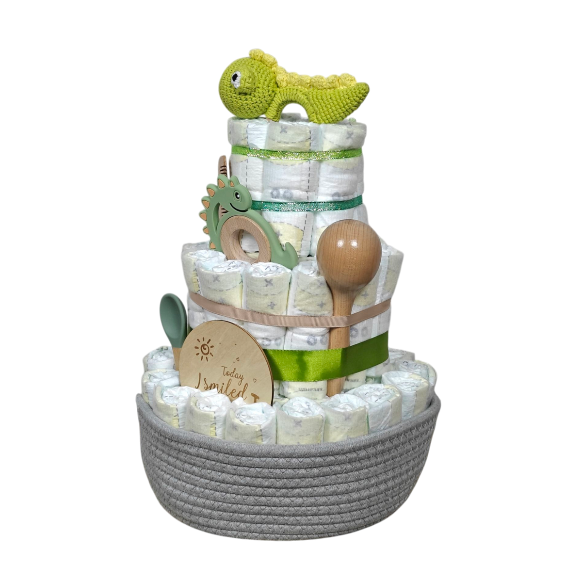 Die Hello World Windeltorte Dino [25x38cm], mit natürlichen Baby-Essentials, grünen und Holz-Babyspielzeugen, Holzlöffeln & gehäkeltem Dino in einem grauen Korb, ist das perfekte Geschenk zur Geburt.