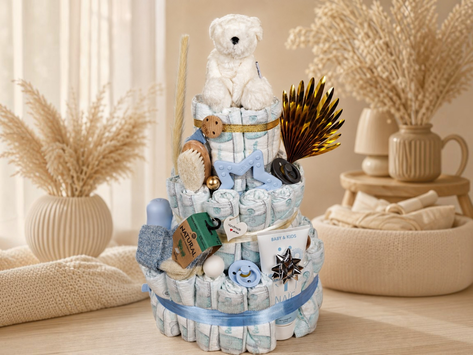 Windeltorte zur Geburt mit Pampers, Babyspielzeug und Pflegeprodukten in Blau